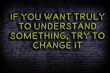 Tuğla duvardaki bilgece alıntıların neon yazıları üzerine gece görüşü