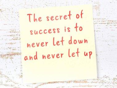 Tahta duvarda asılı sarı yapışkan nota elle yazılmış bilgece bir alıntı.