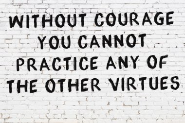 Beyaz tuğla duvara zekice alıntılar yazılı siyah bir yazı.