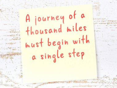 Tahta duvarda el yazısı motivasyon alıntısı olan sarı yapışkan not