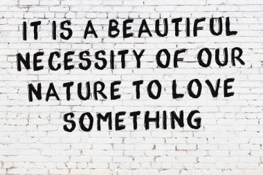 Beyaz tuğla duvara zekice alıntılar yazılı siyah bir yazı.