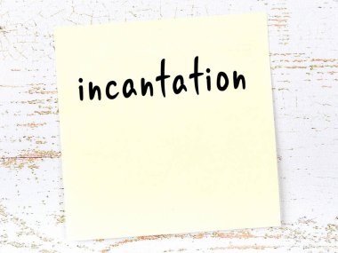 Tahta duvardaki sarı yapışkan notta el yazısıyla yazılmış büyü var.