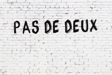 Yazı, beyaz tuğla duvara siyah boya ile yazılmış..