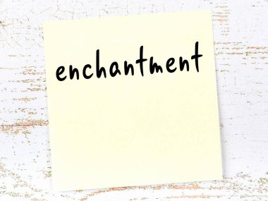 Tahta duvardaki sarı yapışkan notta el yazısıyla yazılmış büyü var.