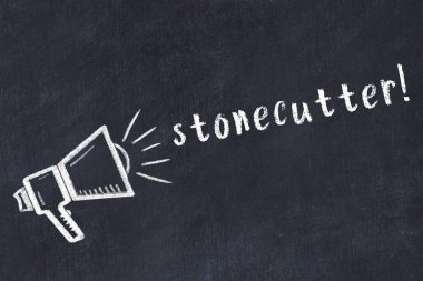 Hoparlörün tebeşir çizimi ve siyah masanın üzerine el yazısıyla taş yazması.