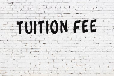 Üzerinde siyah boya ile el yazısıyla harç ücreti yazan beyaz tuğla duvar.