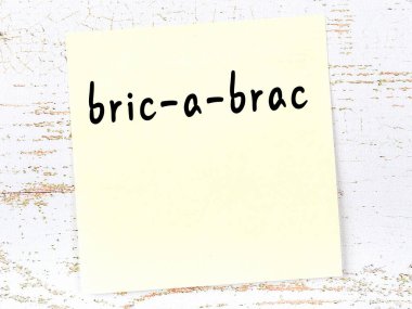Bric-a-brac 'ı hatırlatma kavramı. Tahta duvarda üzerinde yazı olan sarı yapışkan kağıt.