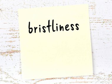 Tahta duvardaki sarı yapışkan notta el yazısıyla yazılmış kıvrımlar var.