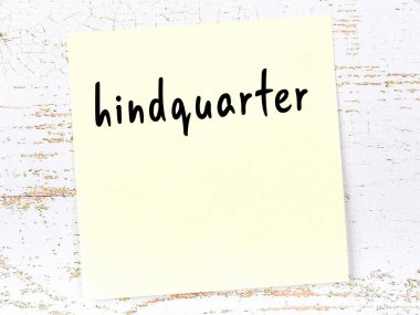 Kıçla ilgili hatırlatma kavramı. Tahta duvarda üzerinde yazı olan sarı yapışkan kağıt.