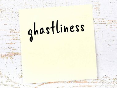 Tahta duvardaki sarı yapışkan notta el yazısıyla yazılmış iğrençlik yazısı var.