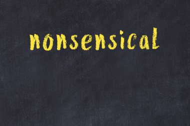 Siyah masanın üzerinde elle yazılmış tebeşir yazısı anlamsız.