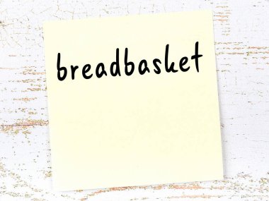 Tahta duvarda el yazısıyla yazılmış ekmek sepeti olan sarı yapışkan bir not.