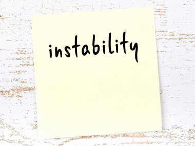 İstikrarsızlığı hatırlatma kavramı. Tahta duvarda üzerinde yazı olan sarı yapışkan kağıt.