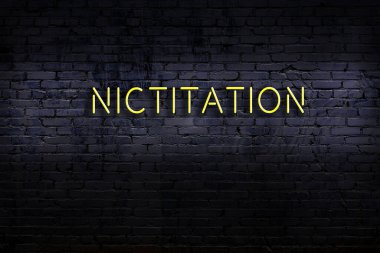 Tuğla duvara yazılı neon tabela. Gece görünümü