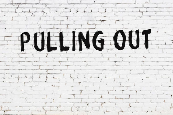 Üzerinde yazı olan beyaz tuğla duvar siyah boyayla el yazısını çıkartıyor.