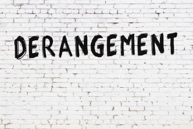 Beyaz tuğla duvarda siyah boyayla yazılmış bir yazı..