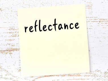 Tahta duvardaki sarı yapışkan notta el yazısı yansıması var.