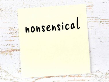 Anlamsız şeyleri hatırlatma kavramı. Tahta duvarda üzerinde yazı olan sarı yapışkan kağıt.