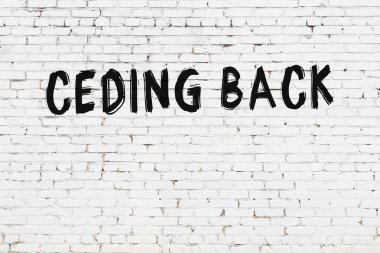 Yazı, beyaz tuğla duvara siyah boya ile yazılmış..