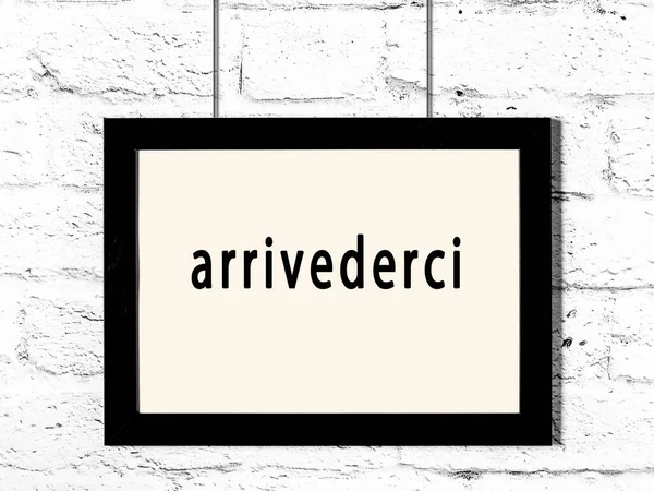 碑文付きの黒い木製のフレーム白いレンガの壁にぶら下がっているArvederci — ストック写真