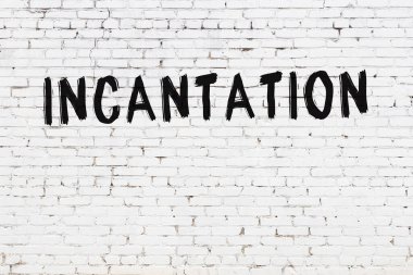 Beyaz tuğladan duvar ve siyah boyalı el yazısı.