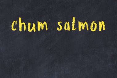 Tebeşir el yazısıyla yazılmış siyah masadaki somon balığı.