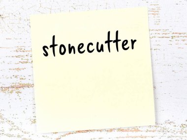 Tahta duvardaki sarı yapışkan notta el yazısıyla yazılmış taş işleyici.