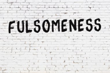 Beyaz tuğladan duvar. Üzerinde yazı var. Dolgunluk, el yazısı ve siyah boya.