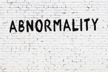 Beyaz tuğlalı duvar. Üzerinde siyah boya ile yazılmış anormallik yazılıymış.