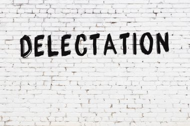 Siyah boyayla el yazısıyla yazılmış beyaz tuğlalı bir duvar.