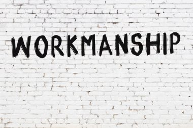 Beyaz tuğlalı duvar. Üzerinde yazı var. Üzerinde siyah boya var.