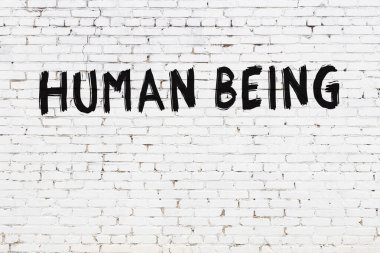 Üzerinde siyah boya olan beyaz tuğla bir duvar.