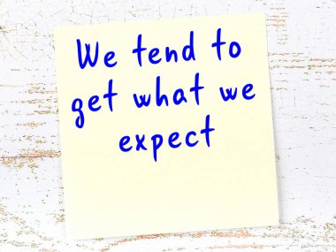 Sarı yapışkan not, ahşap duvarda el yazısıyla yazılmış zekice bir alıntıyla.