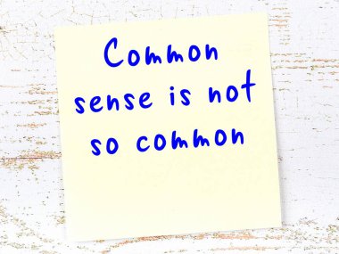 Tahta duvarda el yazısı motivasyon alıntısı olan sarı yapışkan not