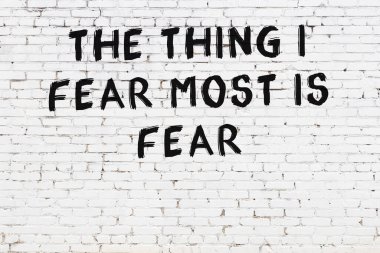 Beyaz tuğla duvara zekice alıntılar yazılı siyah bir yazı.