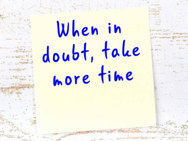 Tahta duvarda el yazısı motivasyon alıntısı olan sarı yapışkan not