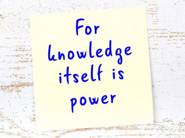 Sarı yapışkan not, ahşap duvarda el yazısıyla yazılmış zekice bir alıntıyla.