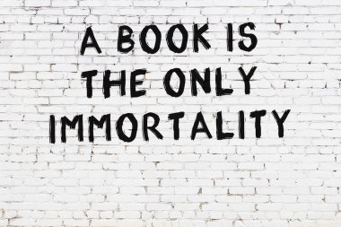 Beyaz tuğla duvara zekice alıntılar yazılı siyah bir yazı.