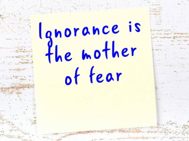 Sarı yapışkan not, ahşap duvarda el yazısıyla yazılmış zekice bir alıntıyla.