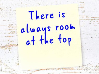 Tahta duvarda asılı sarı yapışkan nota elle yazılmış bilgece bir alıntı.