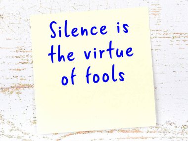 Tahta duvarda asılı sarı yapışkan nota elle yazılmış bilgece bir alıntı.