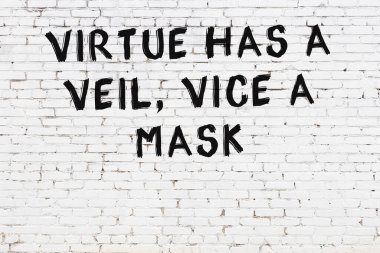 Beyaz tuğla duvara zekice alıntılar yazılı siyah bir yazı.