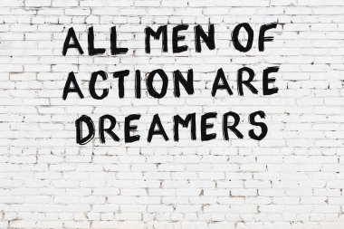 Üzerinde mantıklı alıntıların yazılı olduğu siyah boyanmış beyaz tuğla duvar.