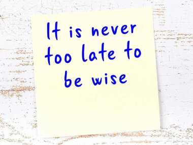 Tahta duvarda asılı sarı yapışkan nota elle yazılmış bilgece bir alıntı.