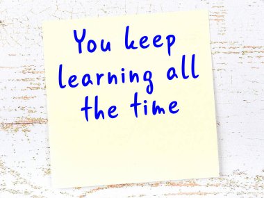 Tahta duvarda el yazısı motivasyon alıntısı olan sarı yapışkan not