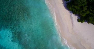 Romantik turist sahili turkuaz okyanusu ve dalgaların yakınındaki temiz kum zeminini yıkıyor.