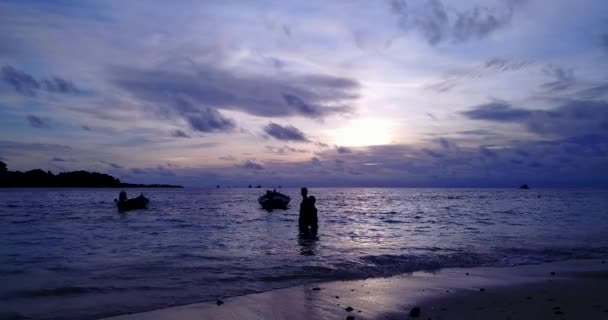 Mladý muž a žena stojí na moři a při západu slunce objímají vodu. Krásný pár odpočívající na tropické letovisko    