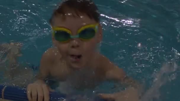 Lindo chico con traje de baño y gafas para practicar natación en la piscina — Vídeos de Stock