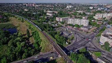 İnsansız hava aracı banliyödeki yolların kesişiminden yükseliyor. Arabalar farklı yönlere gider.