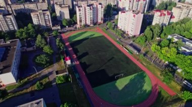 Küçük bir kasabada sokakları olan binaların arkasında futbol sahası boş.